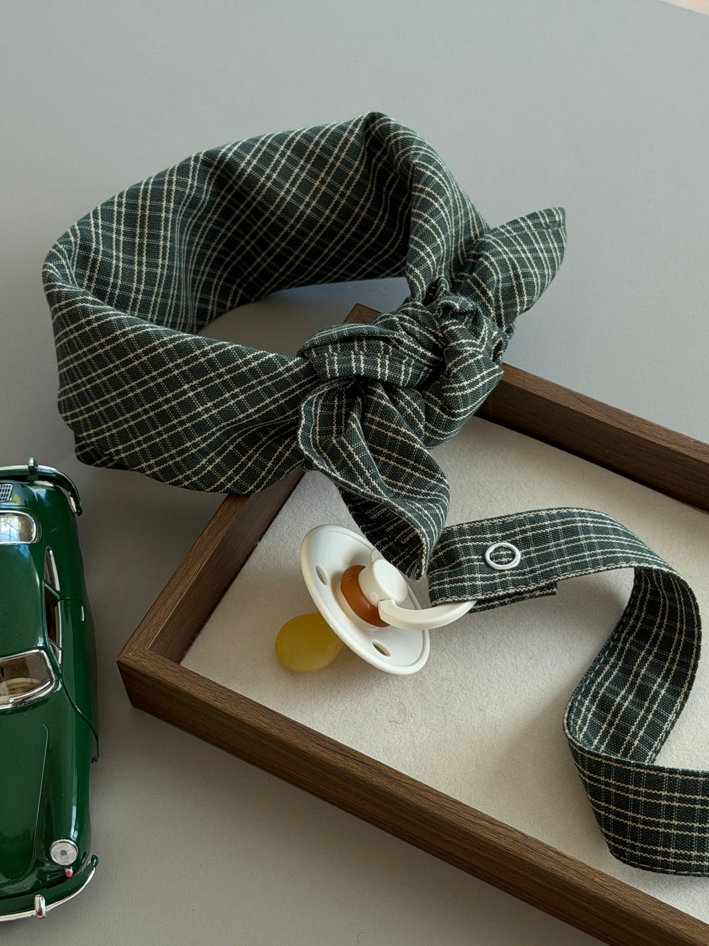 Pine scarf and dummy clip in green check with a dummy and toy car in a wooden tray