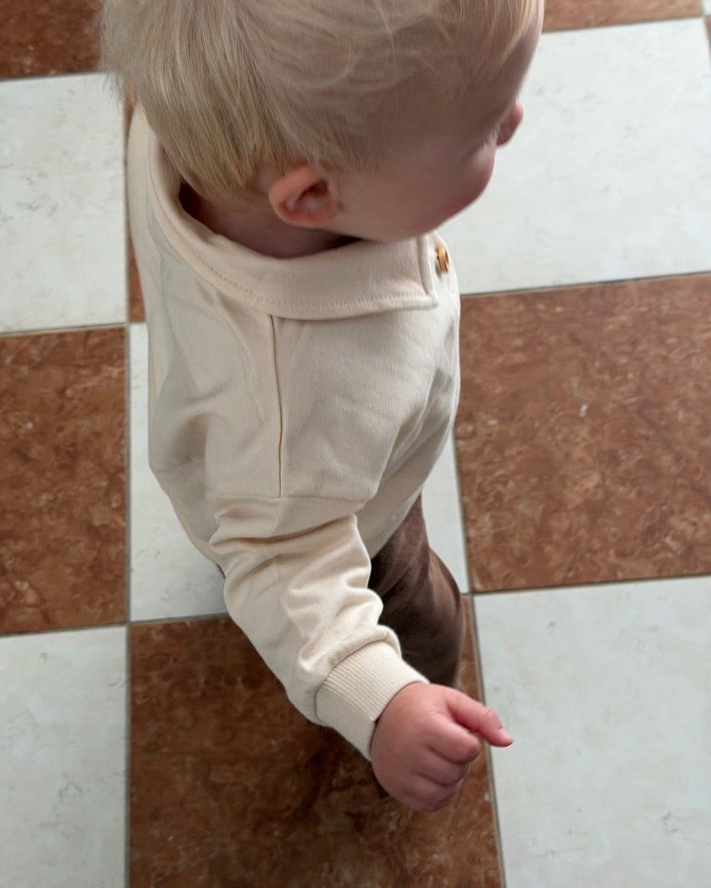Cream long-sleeved polo sweatshirt – boy seen from the side on a chequered floor
