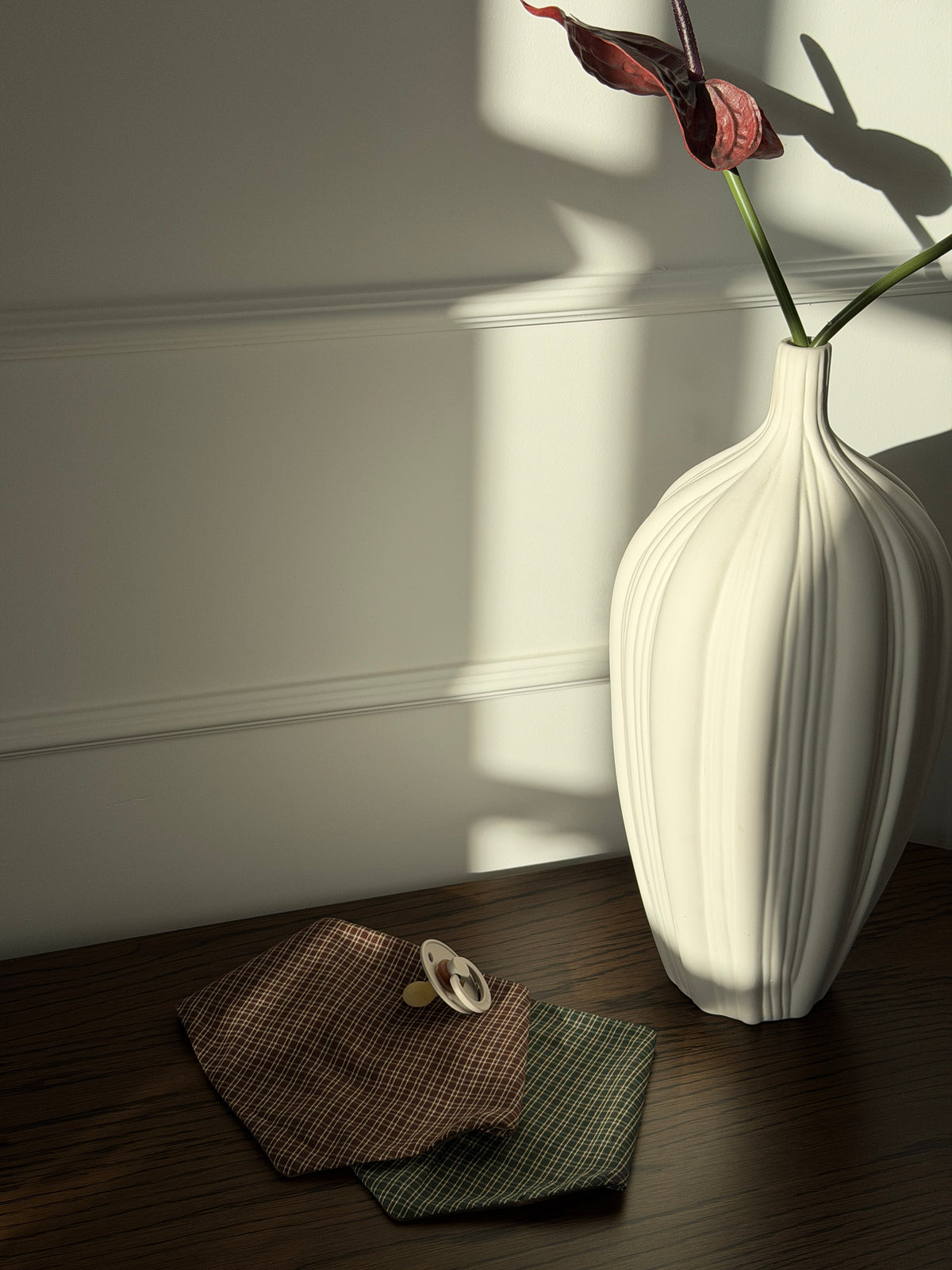 Pecan and Pine bibs with a dummy on a wooden table by a white vase
