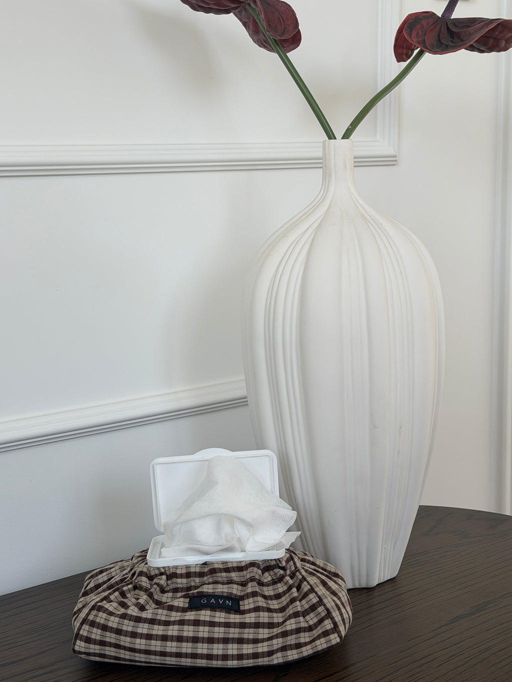Cortado wet wipes case in brown and beige check cotton in front of a white vase