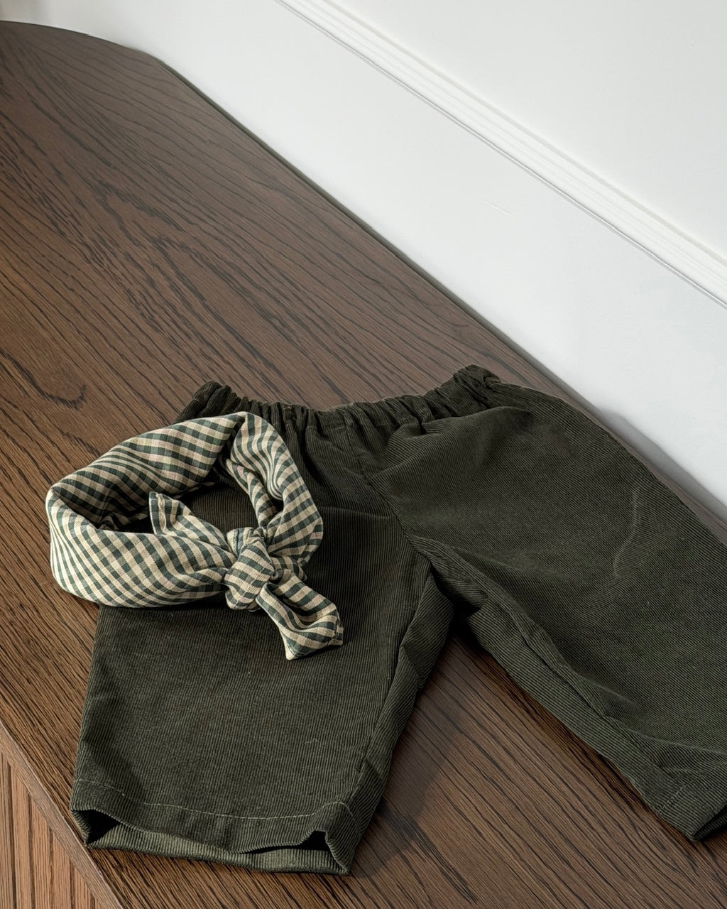 Olive trousers in olive green needlecord with scarf on a wooden bench