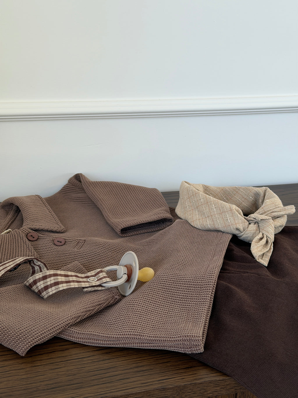 Brown waffle-knit polo shirt laid out with scarf and dummy clip