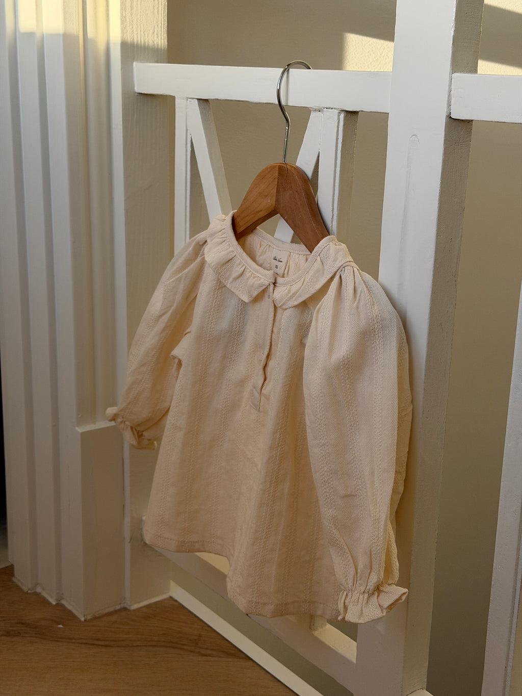 Creme skjortebluse med flæsekrave på bøjle i tremmeseng