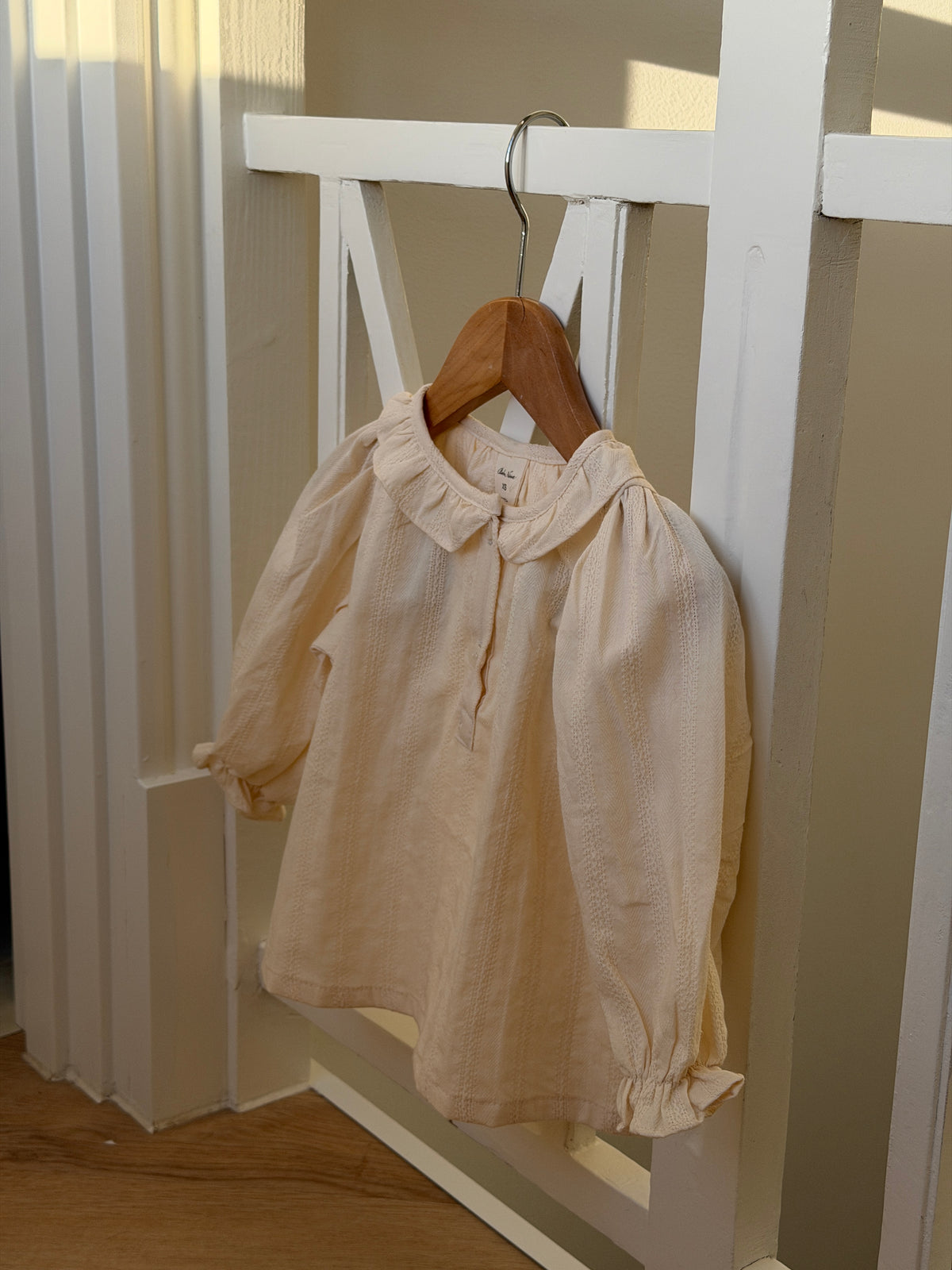 Creme skjortebluse med flæsekrave på bøjle i tremmeseng