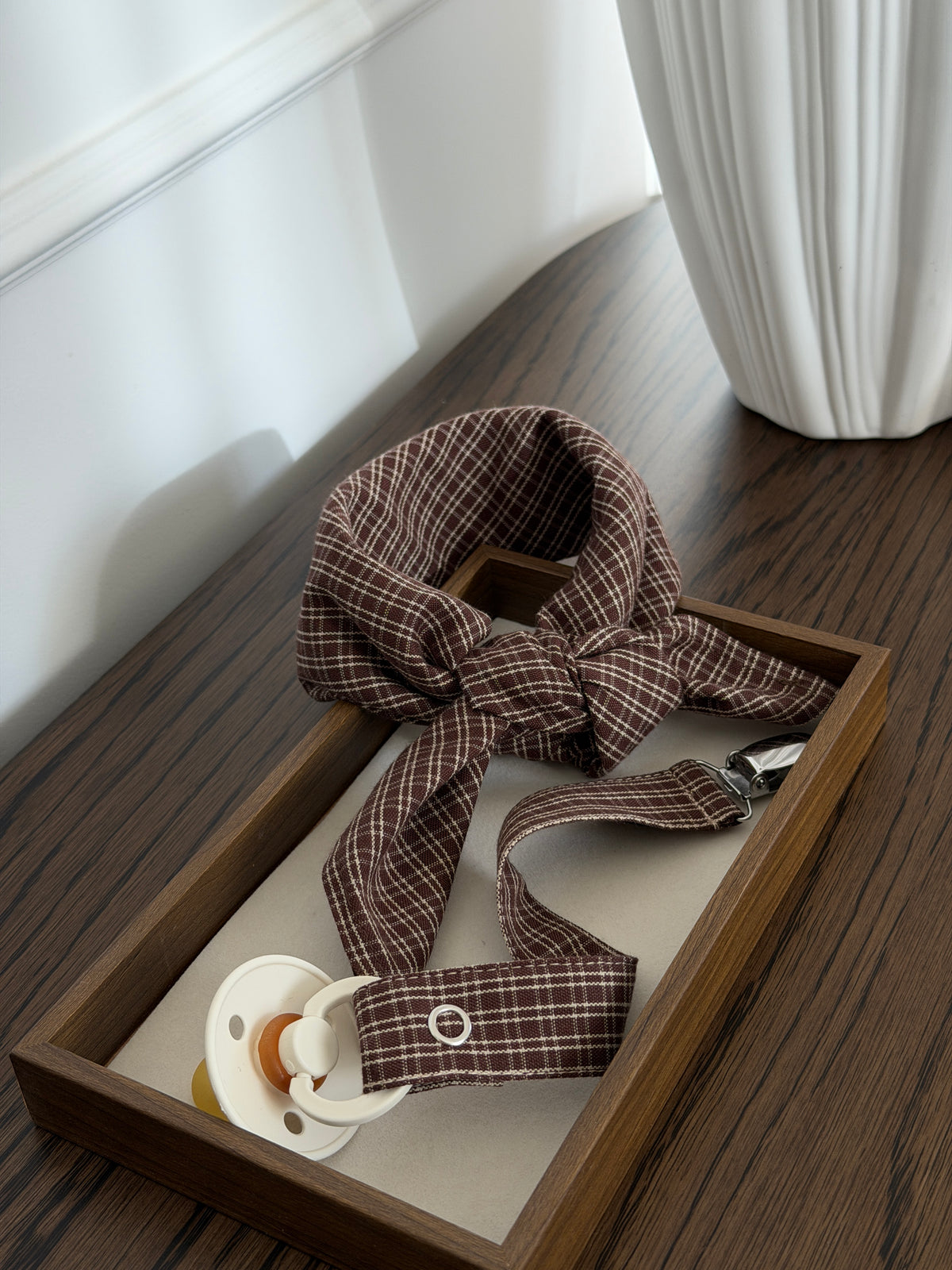 Pecan scarf and dummy clip in reddish-brown check with a dummy in a wooden tray