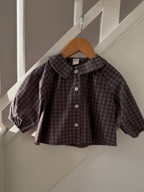 Brown and blue check shirt with a large collar lying on wood