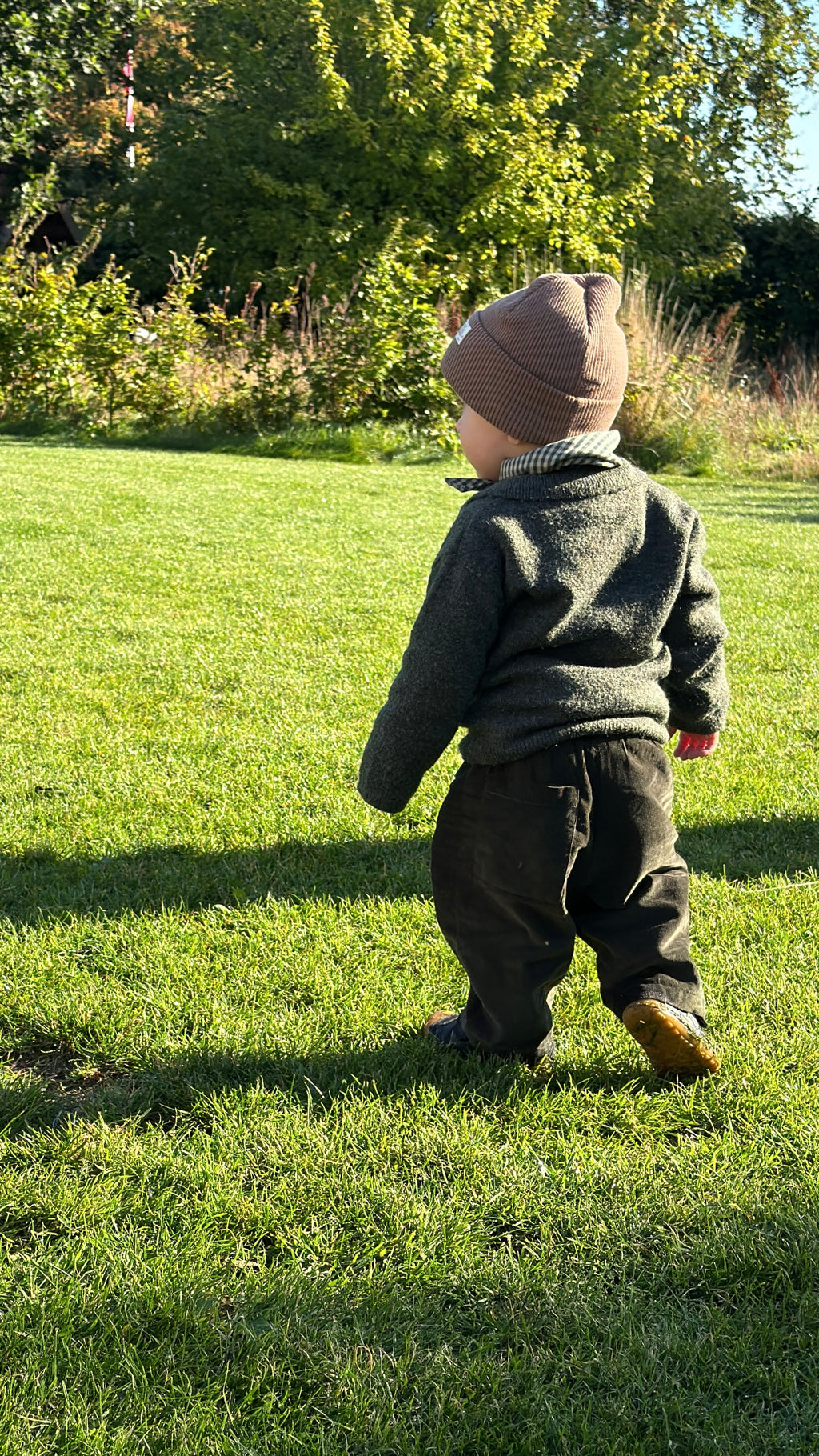 Child walking in the garden in Olive needlecord trousers and Matcha mini scarf