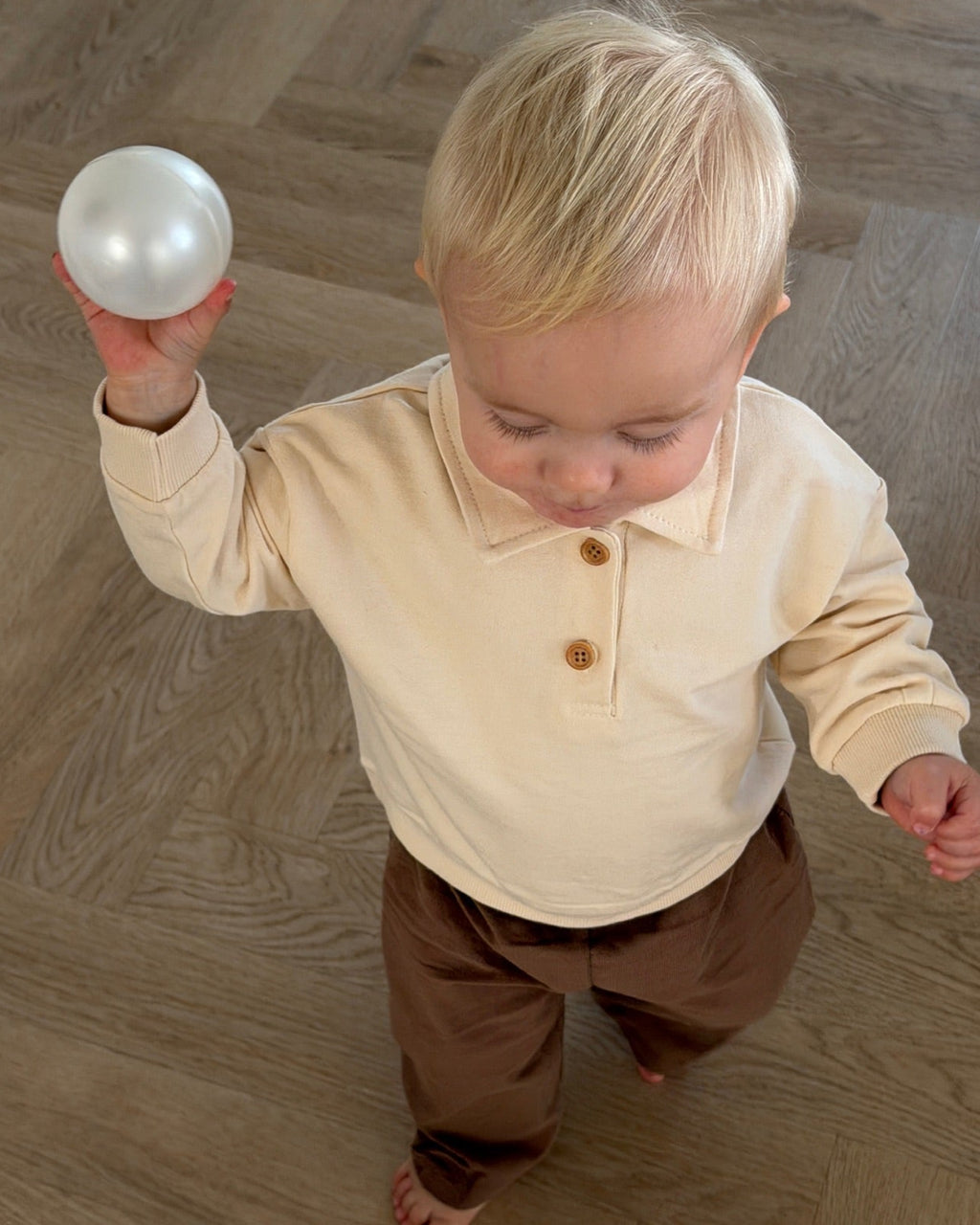 Cream long-sleeved polo sweatshirt – boy playing with a ball