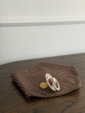 Pecan bib in reddish-brown check cotton with a dummy on a wooden table