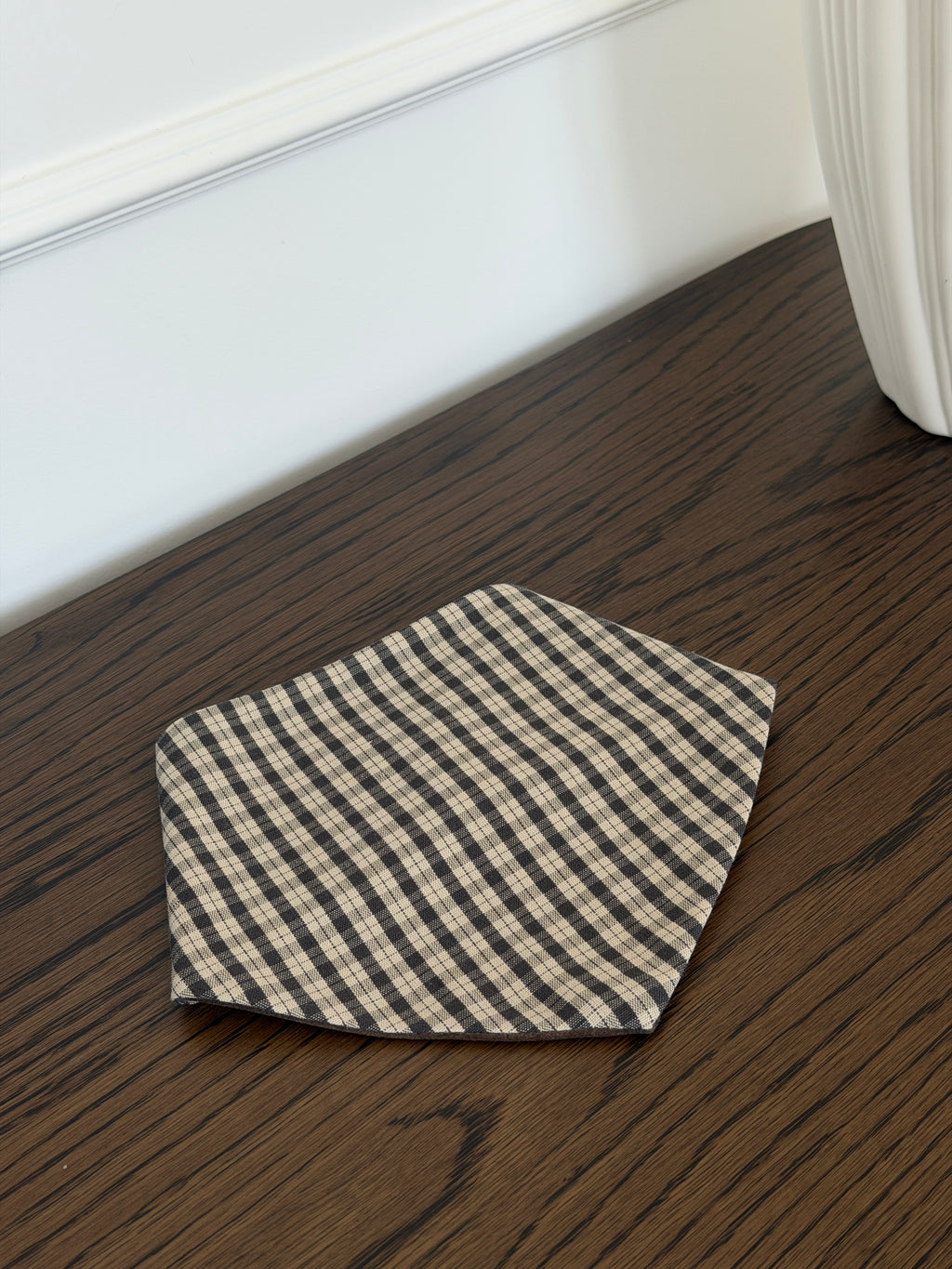 Mocca bib in brown check cotton on a dark wooden table