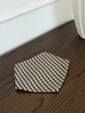 Mocca bib in brown check cotton on a dark wooden table