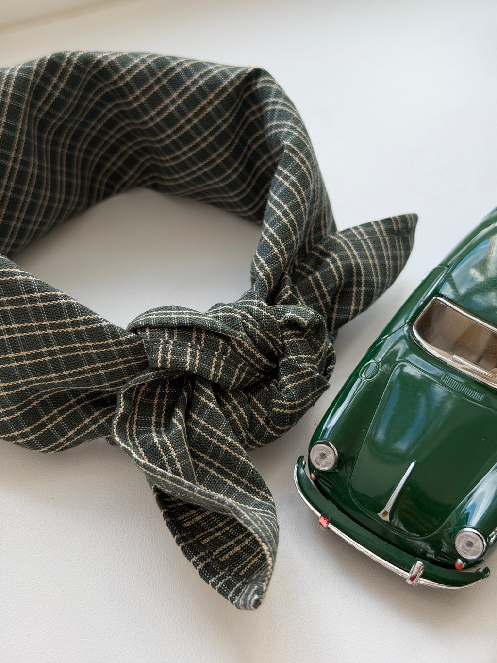 Pine scarf in green check cotton with a toy car on a white table