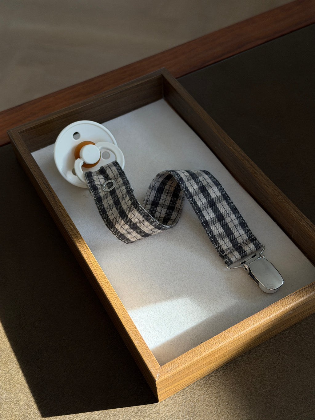 Mocca dummy clip in brown check cotton with a dummy in a wooden tray