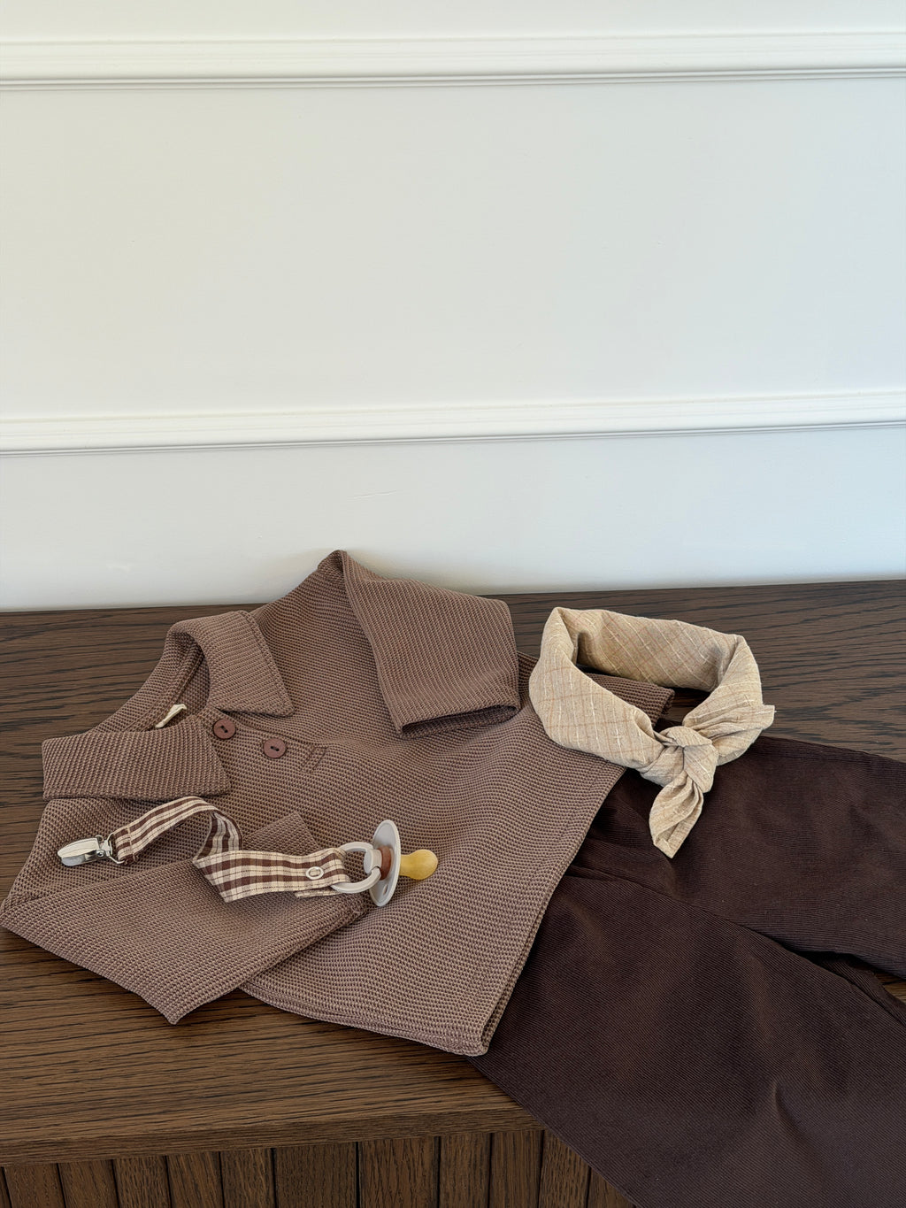 Handpicked brown waffle-knit polo shirt laid out with scarf and dummy clip