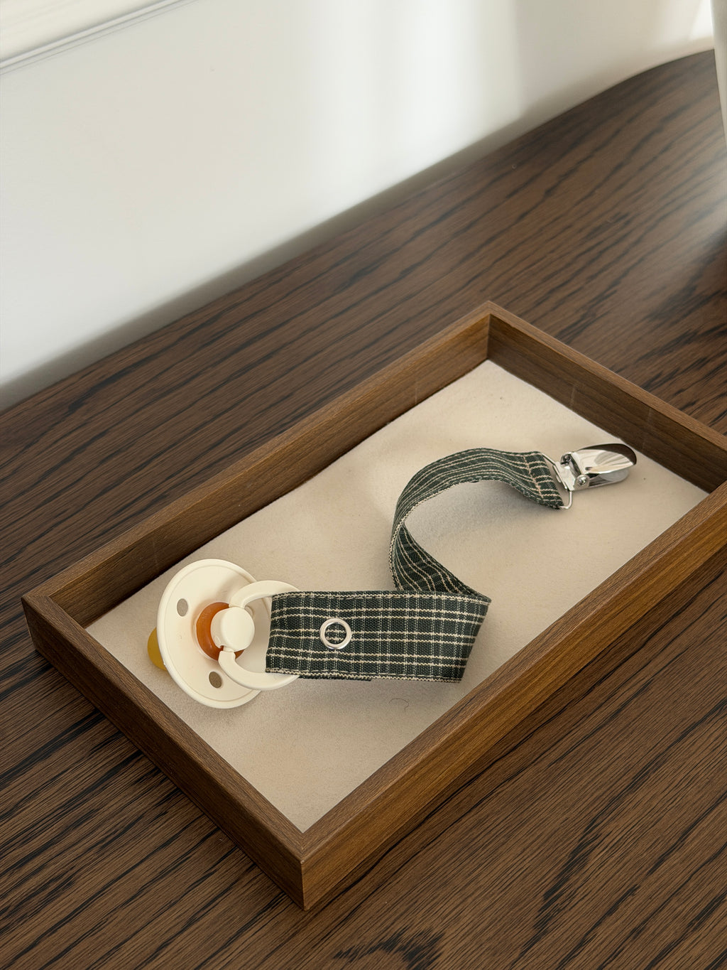 Close-up of Pine dummy clip in green check with a dummy in a wooden tray