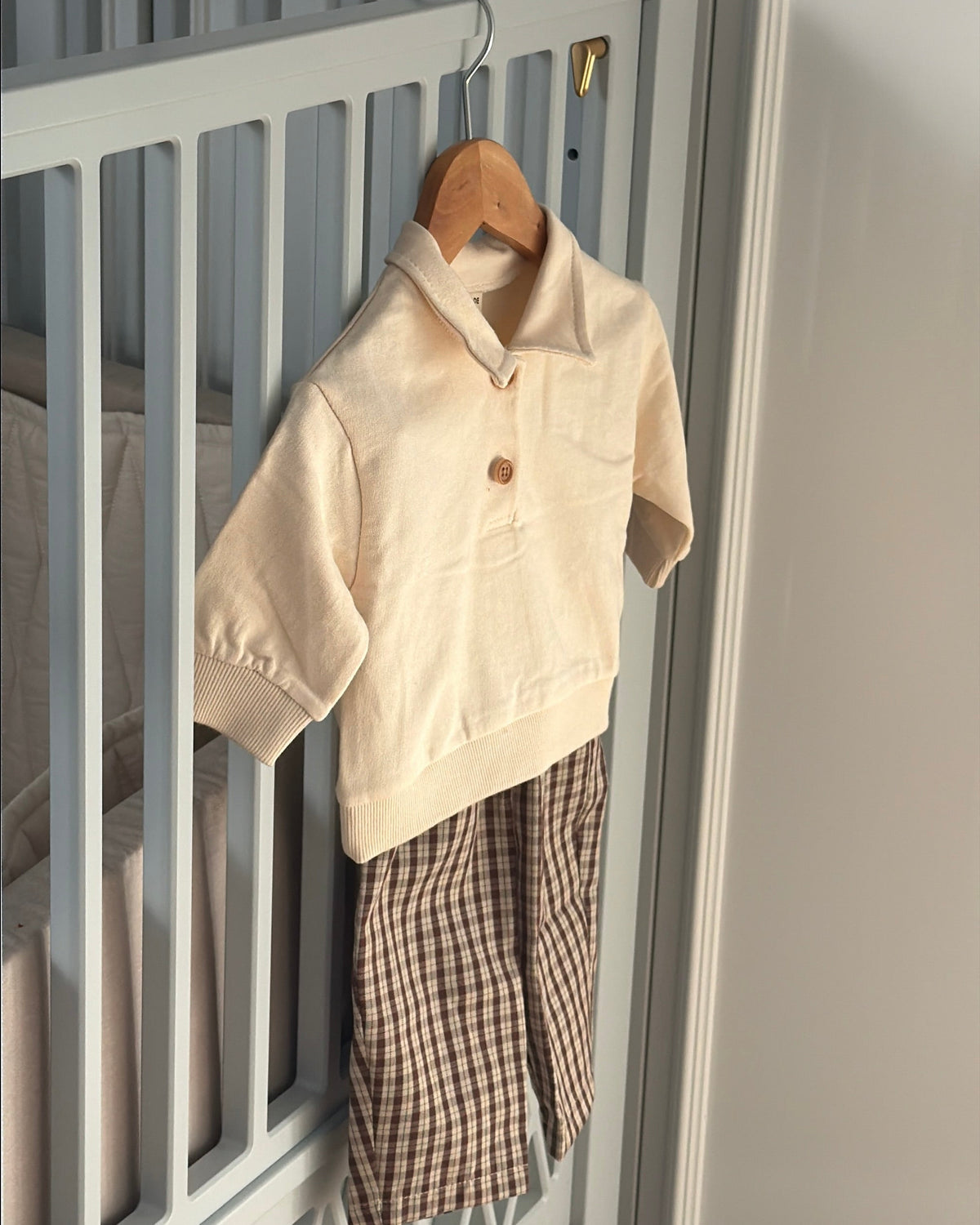 Cream long-sleeved polo sweatshirt on a hanger with checked trousers