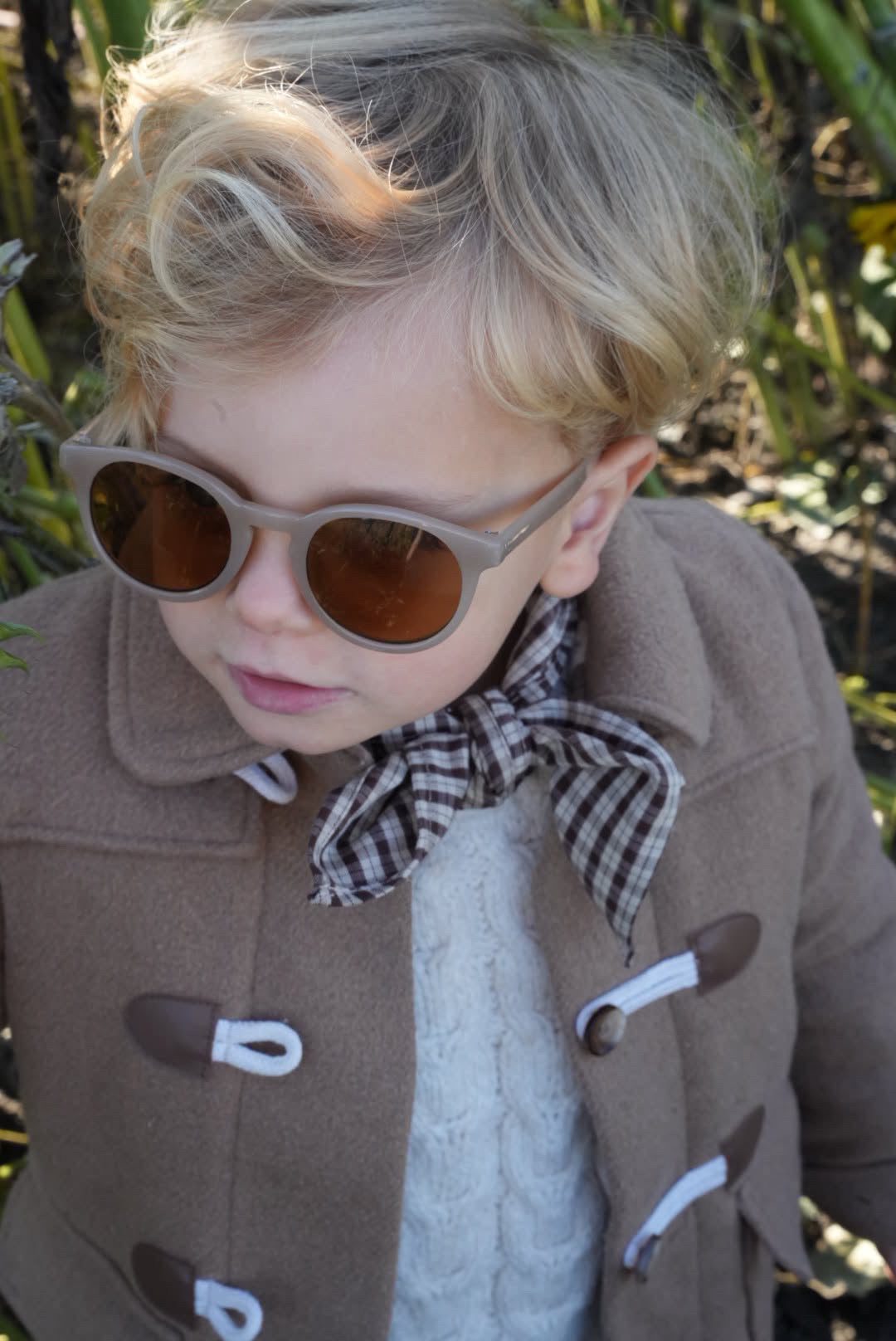 Child with a Cortado scarf in brown and beige check tied at the neck under a coat