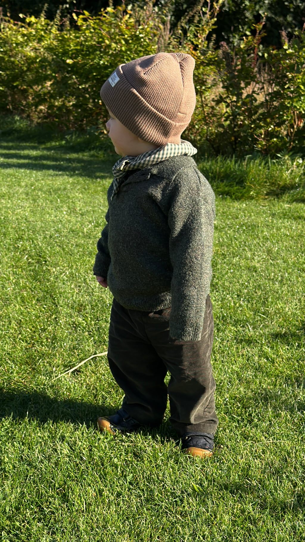 Child in Olive trousers in olive green needlecord and Matcha mini scarf in the garden