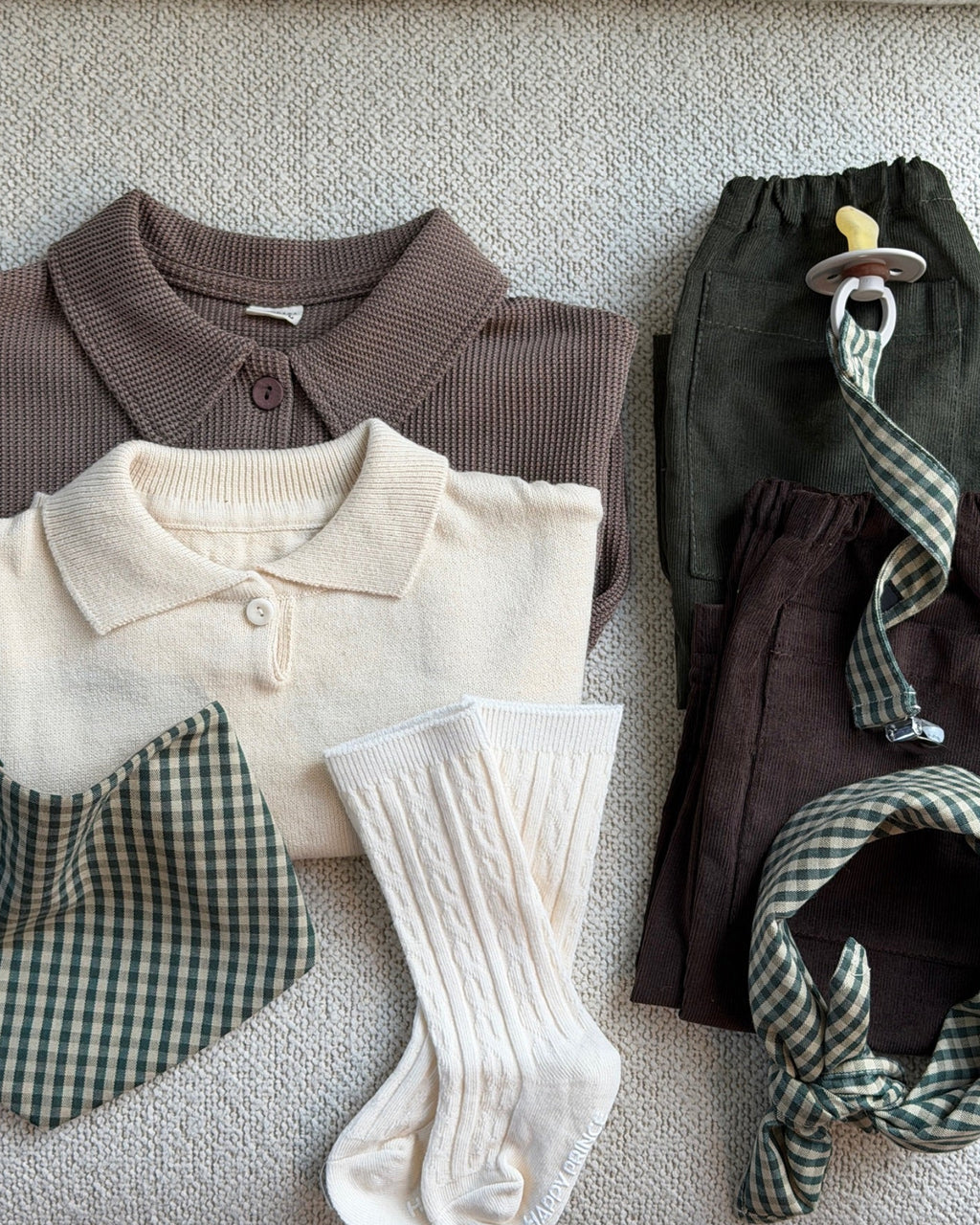 Creme strømper i kabelstrik i flatlay med bluse, hagesmæk og bukser