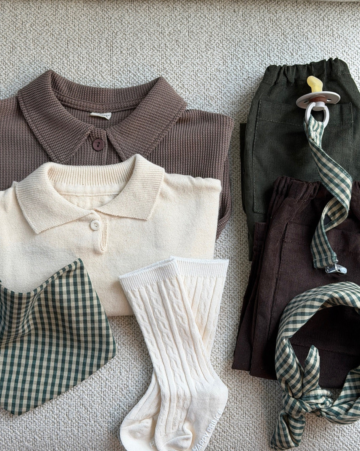 Creme strømper i kabelstrik i flatlay med bluse, hagesmæk og bukser