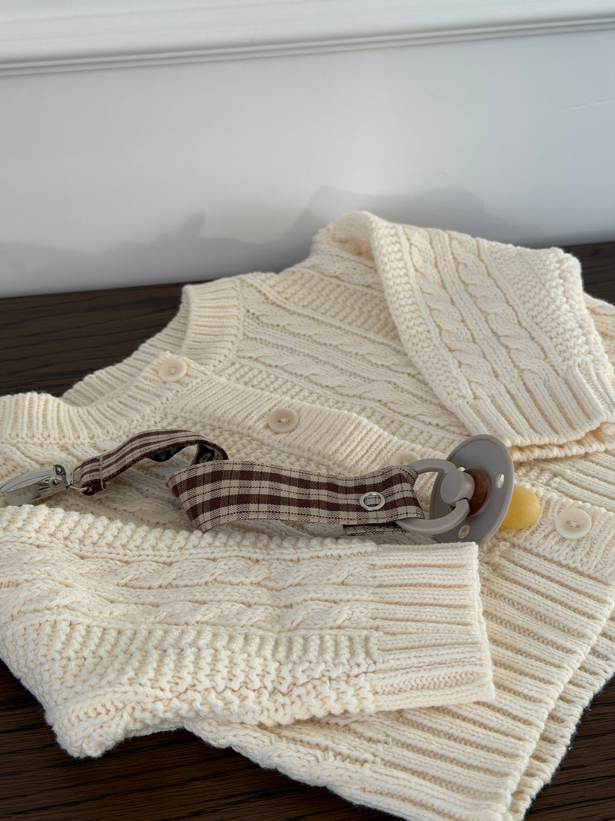 Creme kabelstrikket cardigan liggende med strømper