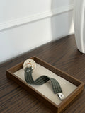 Pine dummy clip in green check cotton with a dummy in a wooden tray
