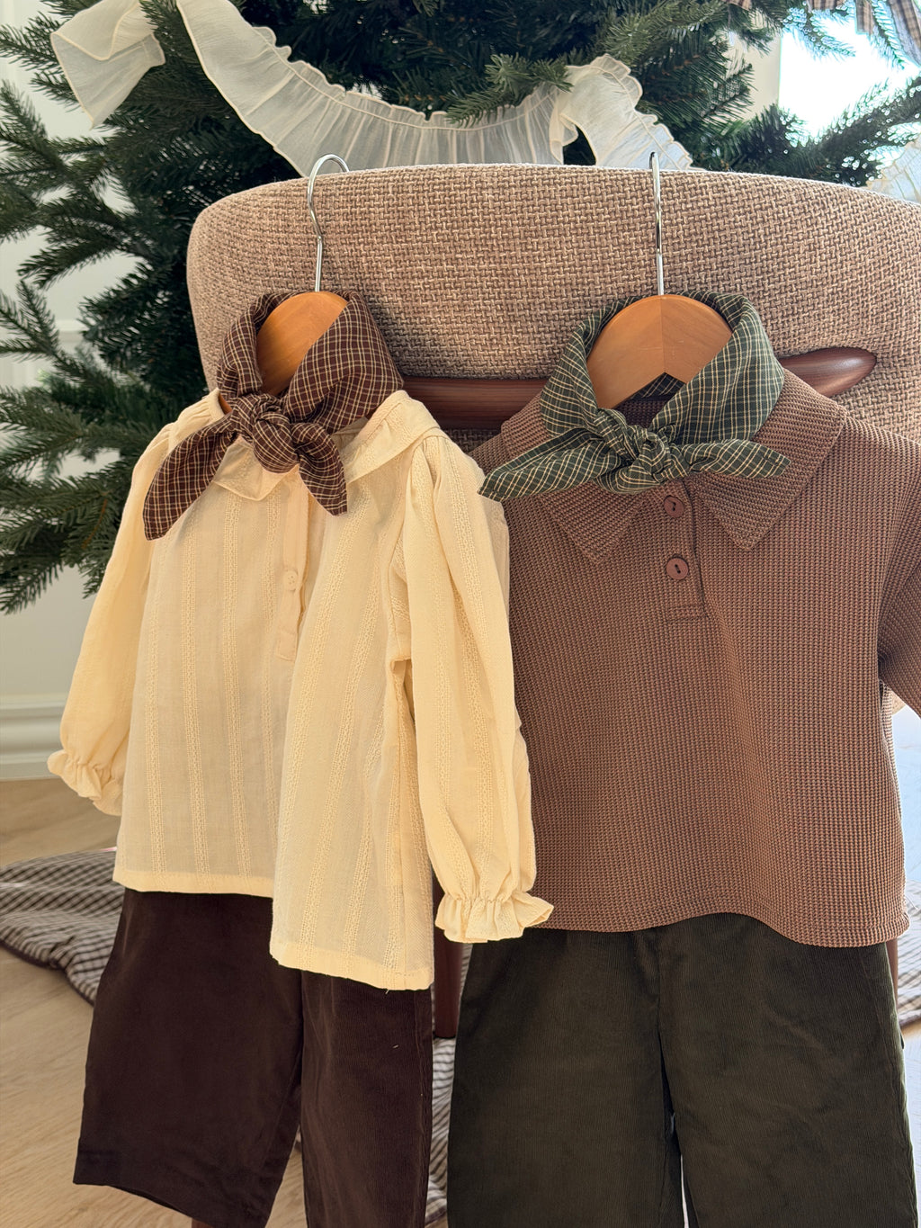 Pecan and Pine checked scarves on hangers with a blouse, polo and trousers by a Christmas tree