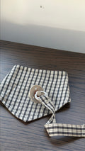 Mocca bib in brown check cotton with dummy clip on a wooden table