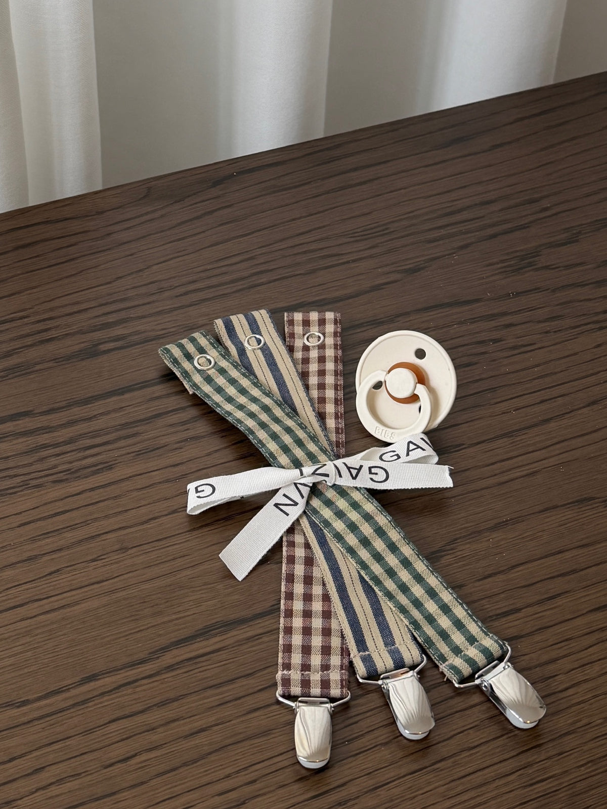 Three checked dummy clips with metal clips and a dummy on a dark wooden table